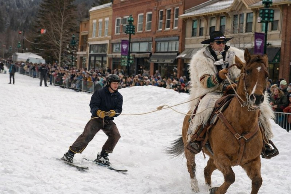 Skiing behind a horse in snow.