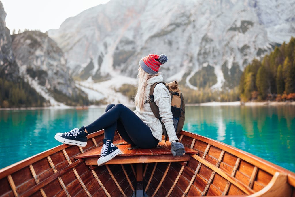 A woman enjoys a scenic boat ride on Lake Braies, surrounded by stunning mountains.